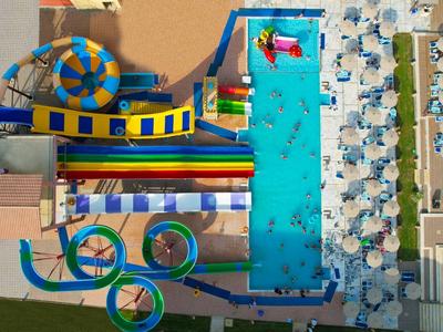 Luchtfoto van een waterpark met zwembaden, glijbanen en parasols bij een hotel.