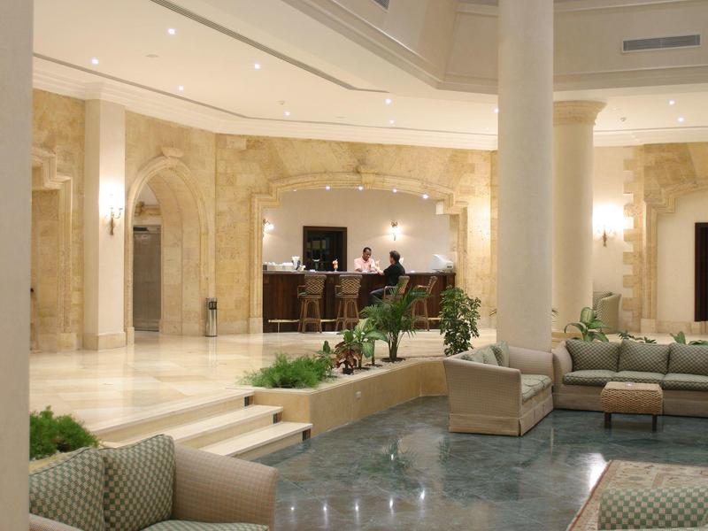 Große, helle Hotellobby mit Marmorboden, Säulen, Sofagruppen und Rezeption im Hintergrund.