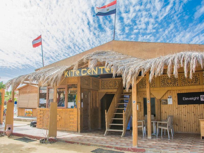 Holzgebäude mit Strohdach und Flaggen unter blauem Himmel bei sonnigem Wetter