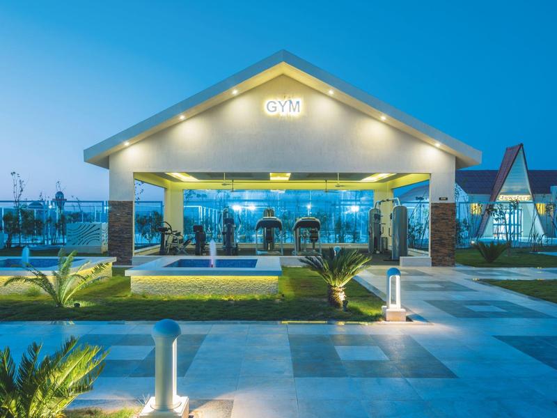 Hôtel moderne éclairé au crépuscule avec pelouse bien entretenue et allée pavée.