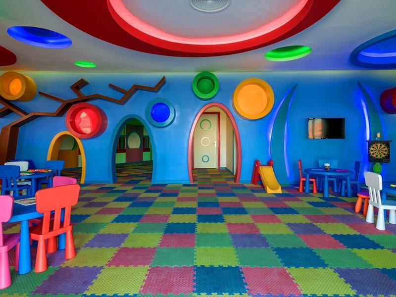 Salle de jeux colorée avec décoration ludique et chaises multicolores pour enfants.