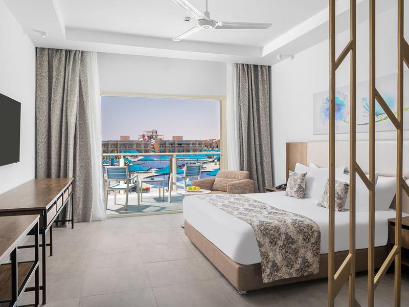 Chambre d'hôtel lumineuse avec balcon donnant sur la mer et meubles modernes.