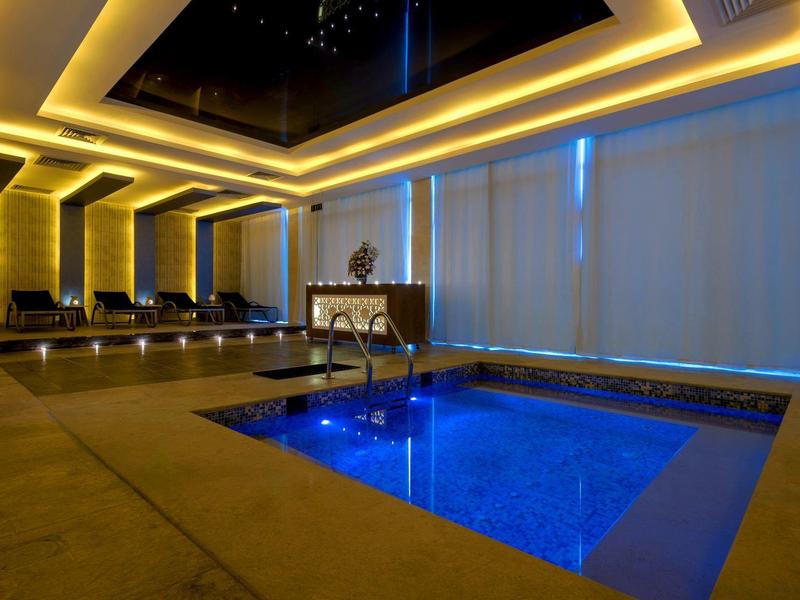 Piscine intérieure luxueuse avec éclairage bleu et ambiance chaleureuse dans un hôtel.