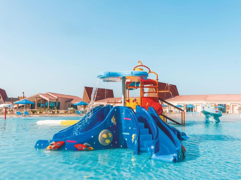 Aire de jeux aquatique bleue dans une piscine sous un ciel dégagé.