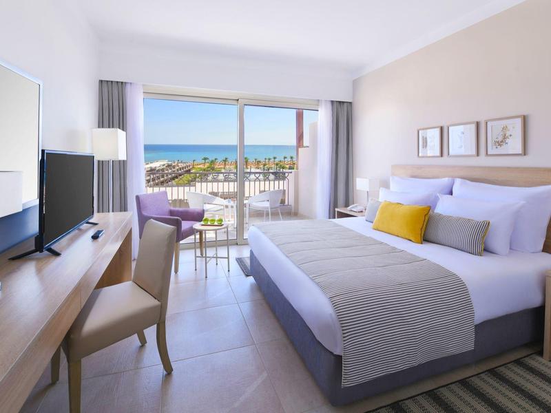 Chambre d'hôtel moderne avec balcon offrant vue sur la mer et décor épuré.