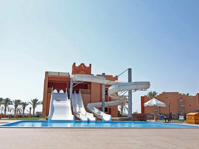 Wasserpark mit Rutschen und Pool vor einem Hotelgebäude bei klarem Himmel.
