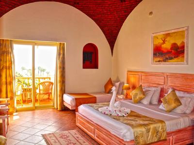 Gemütliches Hotelzimmer mit Doppelbett, Einzelbett, Terrassentür, warmen Farbtönen und Wandbild.