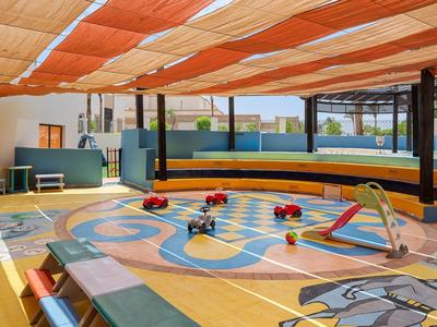 Kinder-Bad mit buntem Muster, Spielzeugbooten und orange-weißen Sonnensegeln auf dem Dach.