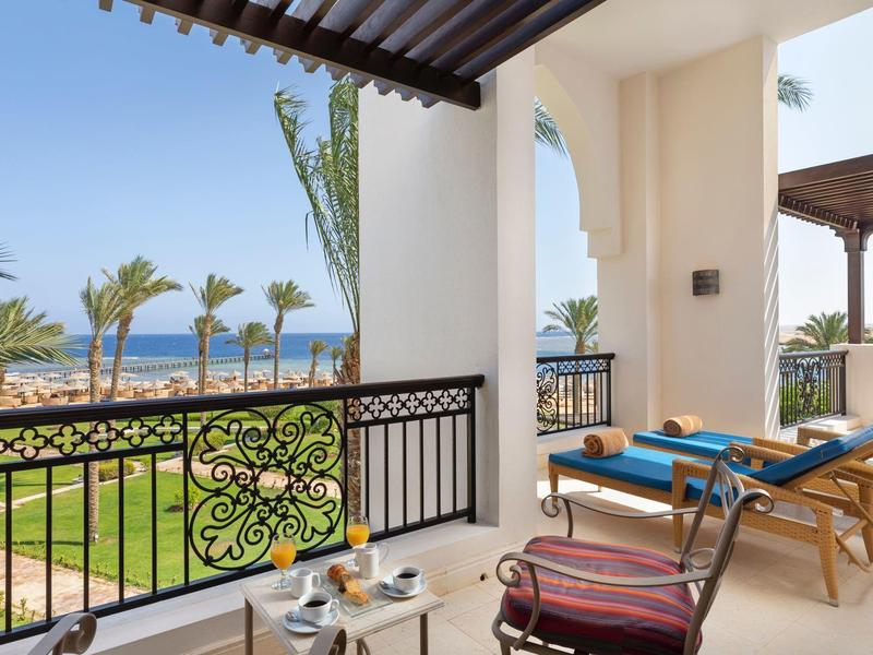 Balkon hotelowy z leżakami z widokiem na morze i ogród.