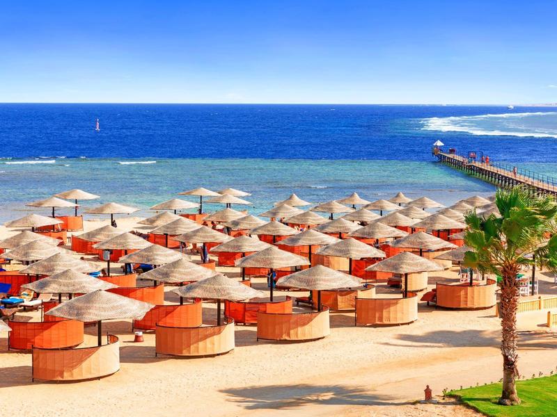 Słoneczna plaża z parasolami i niebieskim morzem na horyzoncie.