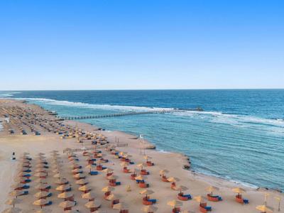 Strand mit Sonnenschirmen und ruhigem blauem Meer unter klarem Himmel