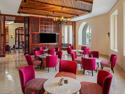 Eleganter Hotel-Loungeraum mit roten Sesseln, runden Tischen und dekorativem Holzdecke.