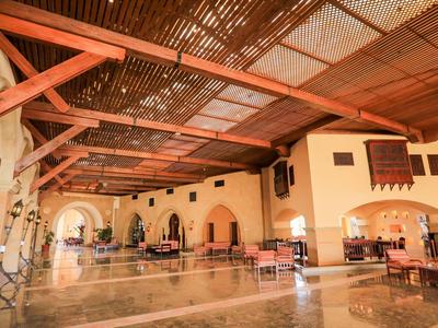 Grote overdekte binnenruimte met houten balken, stoelen en tafels in een hotel.