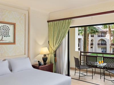 Gezellige hotelkamer met groot bed, lamp en balkon met tafel en stoelen.