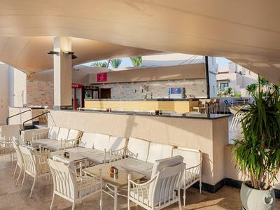 Terasa baru s bílými židlemi a zelenými rostlinami pod zastřešením.