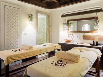 Spa místnost se dvěma masážními stoly a zen dekorací.