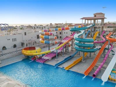 Kleurrijk waterpark met glijbanen en zwembad in een hotelcomplex onder een heldere lucht.