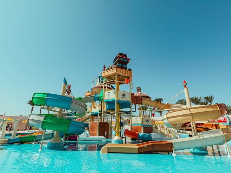 Vodní park s barevnými skluzavkami nad modrým bazénem.