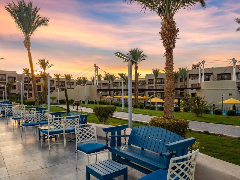 Terasa s modrými stoly a židlemi v hotelu při západu slunce.