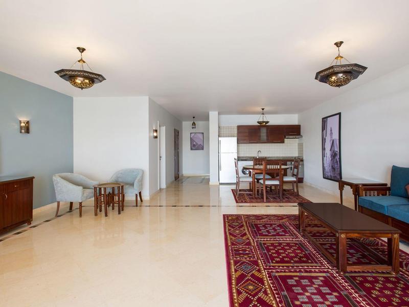 Ruime hotelwoonkamer met eethoek, tv en tapijtvloer