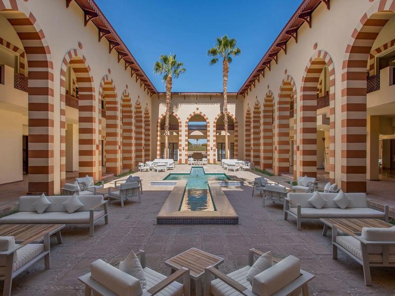 Binnenplaats met moderne loungeset en fontein in gerestaureerd gebouw met arcades.