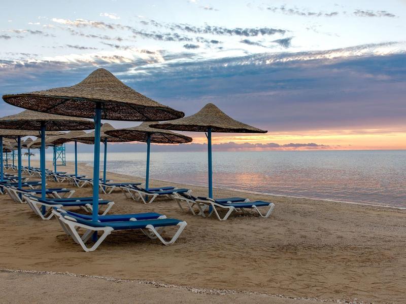 Lege strandstoelen met parasols bij zonsopgang op een rustige strand.