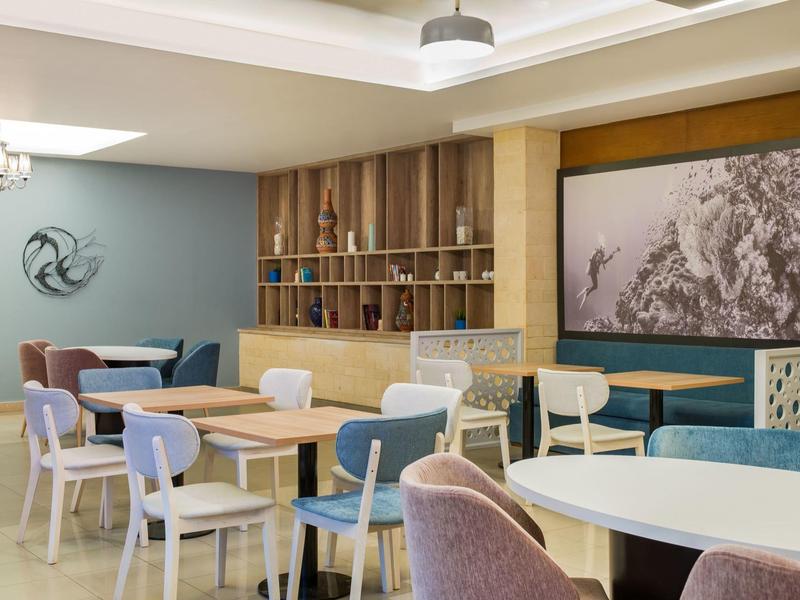 Moderne hotel loungeruimte met diverse zitplaatsen en rustige kleurstelling.