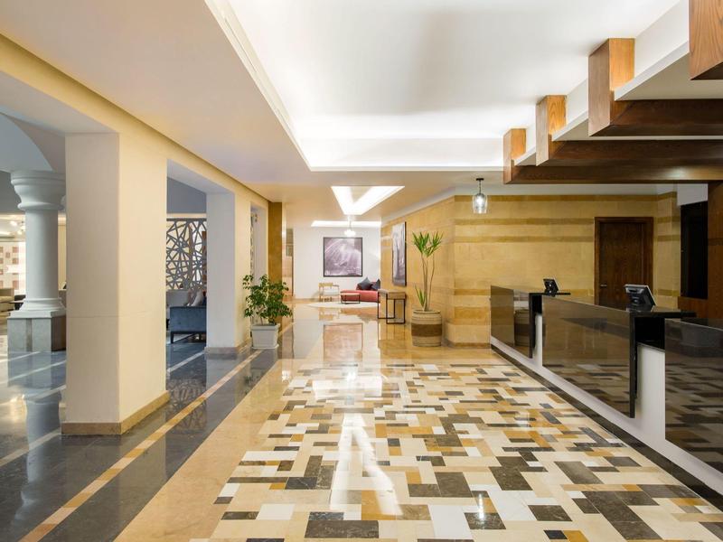 Heldere hotellobby met betegelde vloer, receptiebalie en decoratieve elementen.