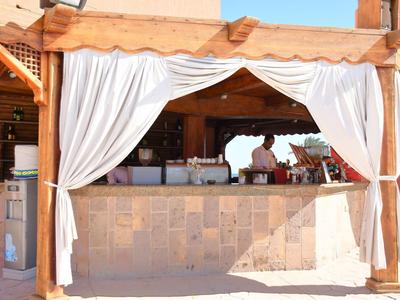 Bar na świeżym powietrzu z białymi zasłonami i jasnym drewnem pod czystym niebem.