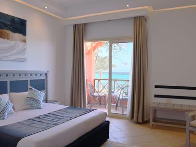 Helles Hotelzimmer mit Doppelbett, Balkon und Blick auf das Meer.