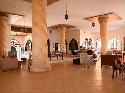 Przestronny hol hotelowy z skręconymi kolumnami i wygodnymi miejscami do siedzenia.