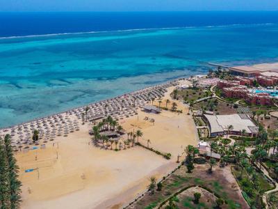 Widok z powietrza na długą piaszczystą plażę z parasolami i turkusowym morzem obok ośrodka wypoczynkowego