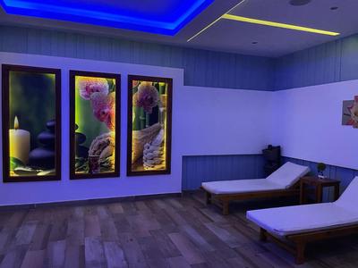 Pokój relaksacyjny z leżakami, uspokajającymi obrazami i miękkim niebieskim oświetleniem.
