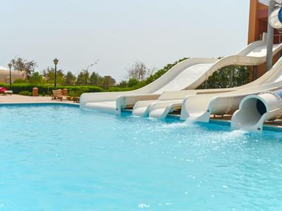 Wasserpark mit mehreren Wasserrutschen, die in einen Pool führen, umgeben von Grünflächen.