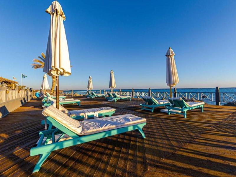 Puste leżaki z parasolami na drewnianym tarasie nad morzem pod czystym niebem.