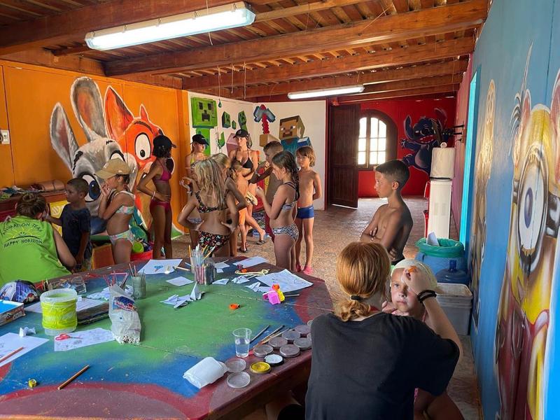 Dzieci tworzące i malujące przy kolorowym stole w pokoju z komiksowymi muralami na ścianach