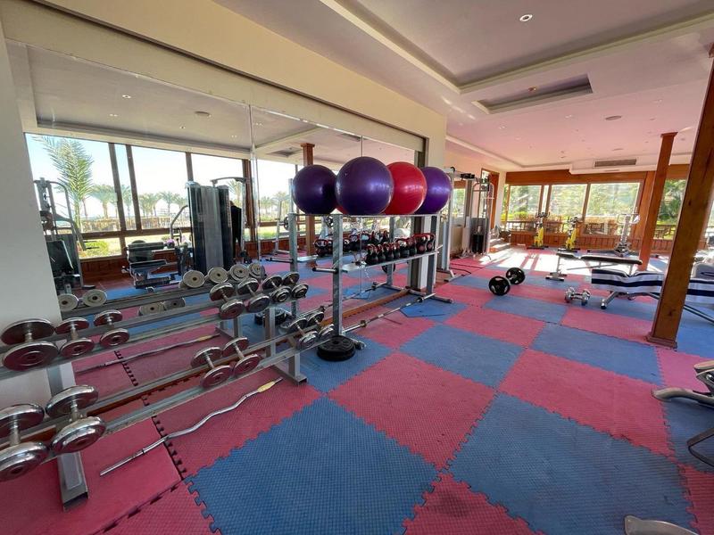 Jasna siłownia z hantlami, piłkami gimnastycznymi i kolorowymi matami.