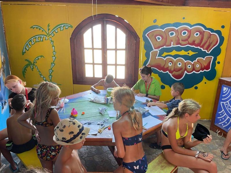 Dzieci malują i robią prace ręczne przy stole w kolorowym, przyjaznym dla dzieci pokoju z dekoracjami na ścianach.