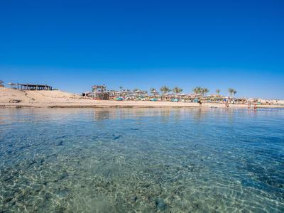 Mare limpido con spiaggia sabbiosa bassa e hotel sullo sfondo sotto un cielo azzurro