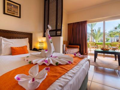 Camera d'hotel accogliente con grande letto, figure decorative in asciugamano e vista sulla terrazza.