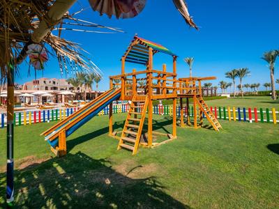 Area giochi colorata con struttura per arrampicata su prato verde sotto un cielo azzurro.