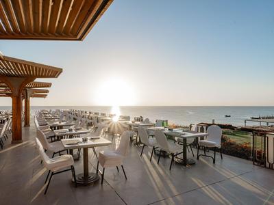 Terrazza dell'hotel con tavoli e sedie con vista sul mare al tramonto.