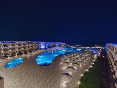 Vista di una piscina d'hotel illuminata con lettini e ombrelloni di notte