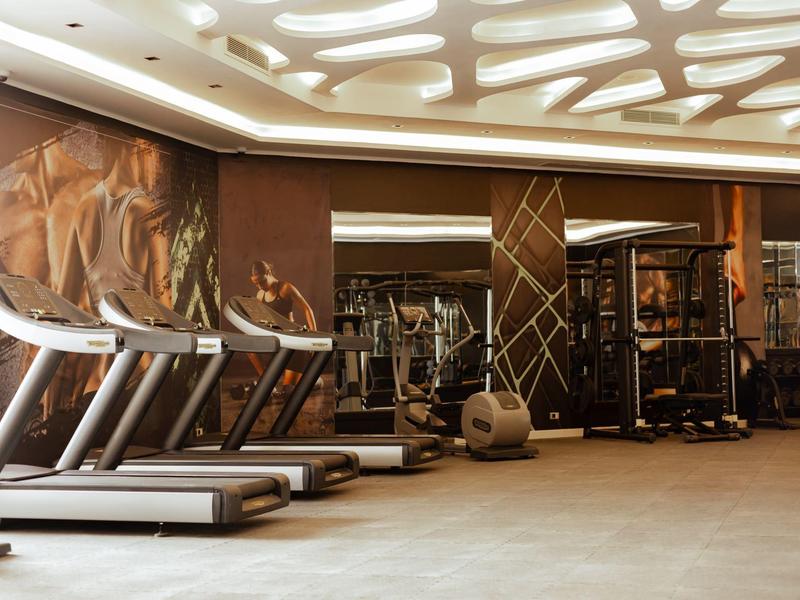 Salle de sport moderne avec tapis roulants et équipements dans une grande pièce.