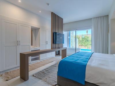 Moderní hotelový pokoj s manželskou postelí, televizí s plochou obrazovkou a výhledem na bazén.