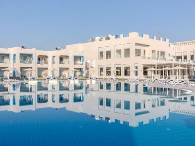 Moderní hotel s bílou fasádou a velkým venkovním bazénem za jasné oblohy.