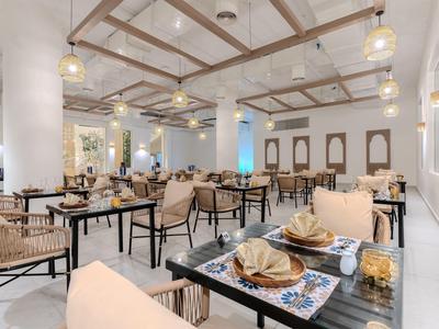 Světlá restaurace s pohodlným posezením a moderním vybavením pro příjemné stravování.