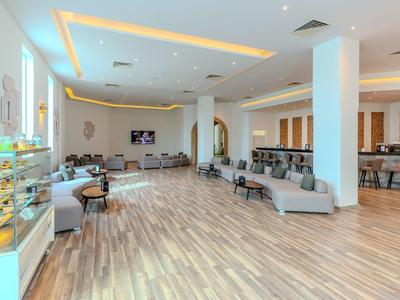 Světlá, moderní hotelová hala se sezením a pultem s pečivem.