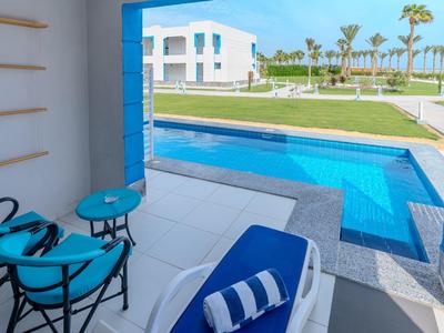 Výhled na bazén a zahradu z terasy s modrým lehátkem a židlemi.