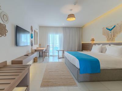 Moderně zařízený hotelový pokoj s dvoulůžkem, pracovním stolem a balkonem.